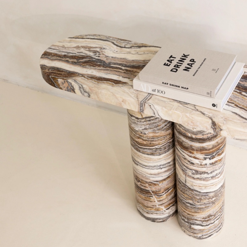 Close-up of striped marble console table with book - modern natural stone accent furniture