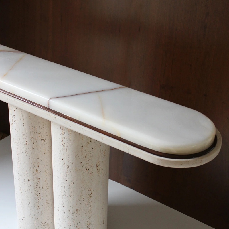 Close-up of double-layered tabletop edge on travertine console table - white onyx with dark metal trim
