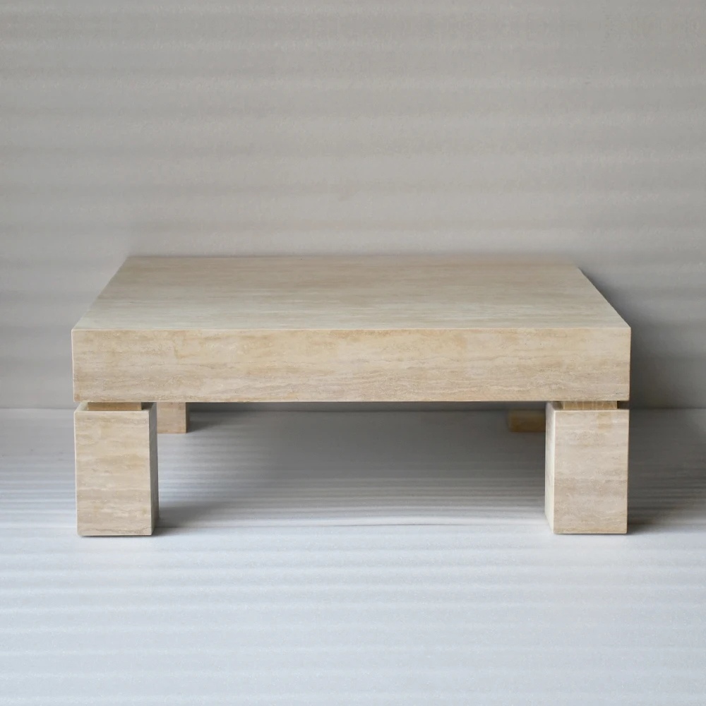 Low‑profile square travertine coffee table with chunky pedestal legs