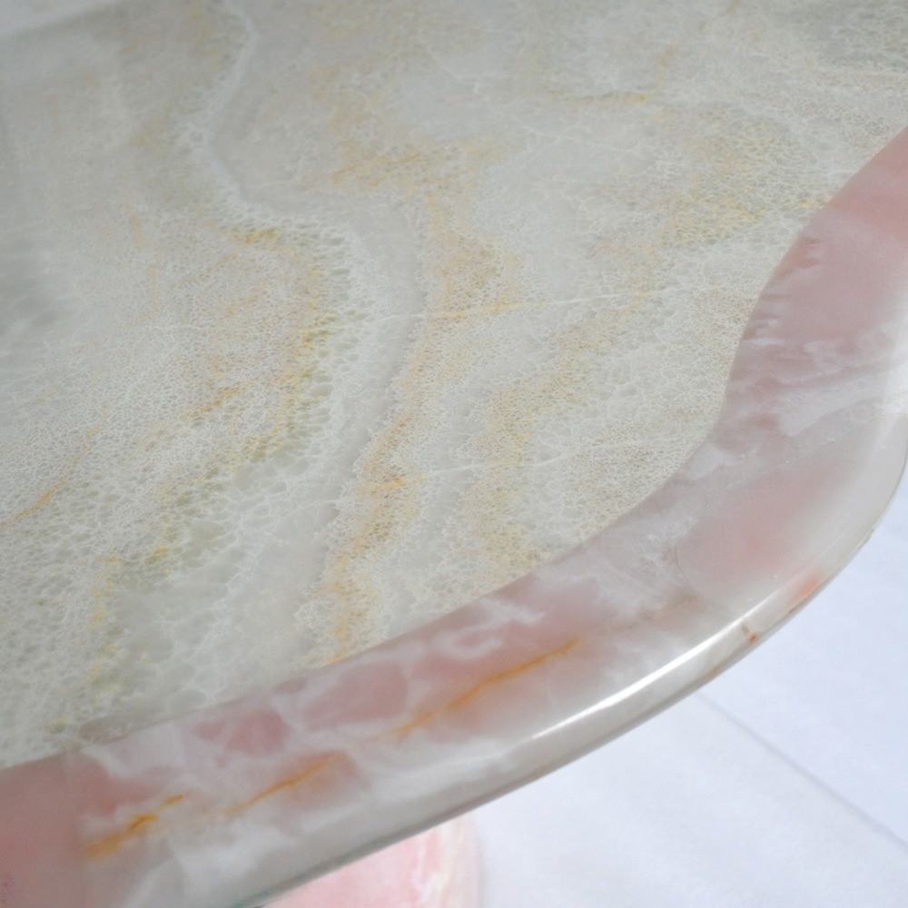 Close‑up of pink onyx tabletop – natural pink‑white‑gold veining and polished glossy surface